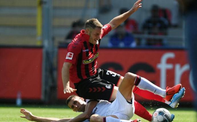 Cagliaris Federico Mattiello (u) trennt Freiburgs Christian Günther per Grätsche vom Ball. Foto: Patrick Seeger