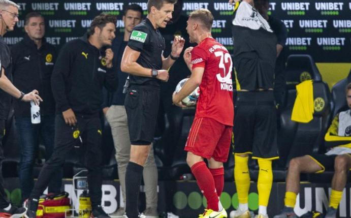 Joshua Kimmich (r) diskutiert nach der Gelben Karte mit Schiedsrichter Daniel Siebert, der ihm für das Foul Sancho nur verwarnte. Foto: Guido Kirchner