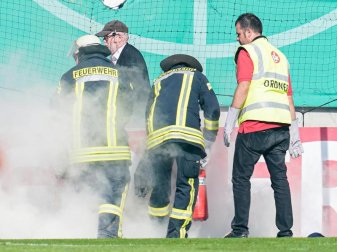 Feuerwehrleute löschen Bengalos aus dem Mainzer Fanblock. Foto: Uwe Anspach Feuerwehrleute löschen Bengalos aus dem Mainzer Fanblock. Foto: Uwe Anspach