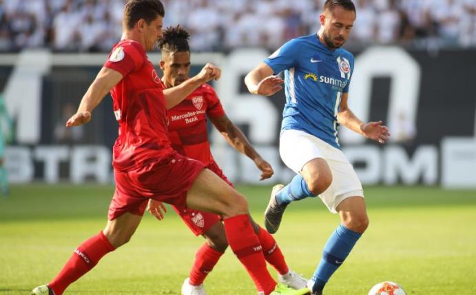 Rostocks Pascal Breier (r) wird von Daniel Didavi (M) und Mario Gomez unter Druck gesetzt. Foto: Danny Gohlke