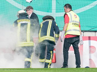 Feuerwehrleute löschen brennende Bengalos, die von Mainzer Fans aufs Spielfeld geworfen wurden. Foto: Uwe Anspach/dpa Feuerwehrleute löschen brennende Bengalos, die von Mainzer Fans aufs Spielfeld geworfen wurden. Foto: Uwe Anspach/dpa
