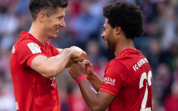 Serge Gnabry (r) gratuliert seinem Bayern-Kollegen Robert Lewandowski zum Torrekord. Foto: Sven Hoppe/dpa