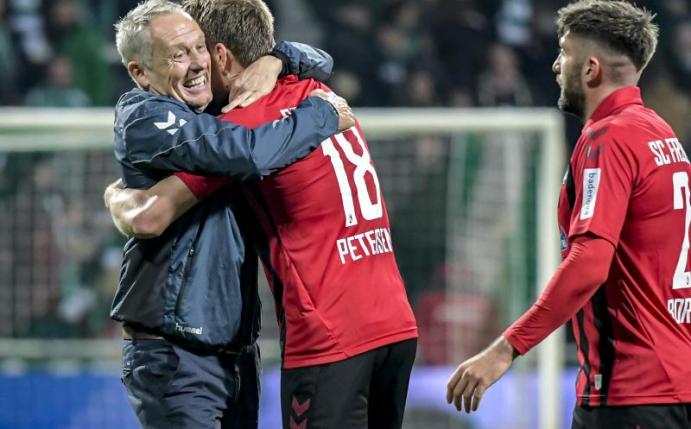 Freiburgs Coach Christian Streich gratuliert seinem Doppeltorschützen Nils Petersen. Foto: Axel Heimken/dpa
