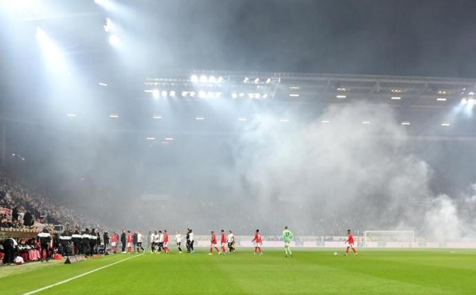 Dichte Rauchschwaden durchziehen das Stadion, nachdem Feuerwerkskörper aus dem Frankfurter Fanblock auf dem Rasen gelandet sind. Foto: Torsten Silz/dpa