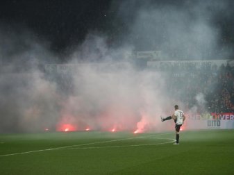 Dichte Rauchschwaden durchziehen das Mainzer Stadion, nachdem Feuerwerkskörper aus dem Gästeblock auf dem Rasen gelandet sind. Foto: Thomas Frey/dpa Dichte Rauchschwaden durchziehen das Mainzer Stadion, nachdem Feuerwerkskörper aus dem Gästeblock auf dem Rasen gelandet sind. Foto: Thomas Frey/dpa