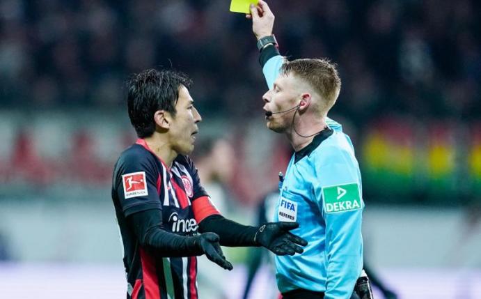 Eintracht-Coach Hütter kritisiert die Leistung des Schiedsrichters: Christian Dingert (r) zeigt Frankfurts Makoto Hasebe (l) gelb. Foto: Uwe Anspach/dpa