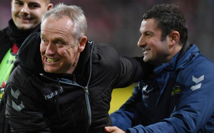 Freiburgs Trainer Christian Streich (M) bejueblt den 1:0-Sieg über den VfL Wolfsburg mit Torwarttrainer Andreas Kronenberg (r). Foto: Patrick Seeger/dpa