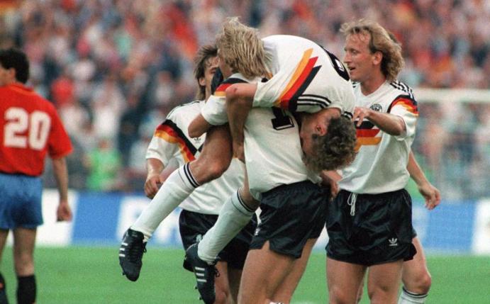 Wurden 1990 zusammen Weltmeister: Jürgen Klinsmann (M, vorn) schultert vor Freude Rudi Völler (M, oben). Foto: dpa/dpa/Archiv/dpa