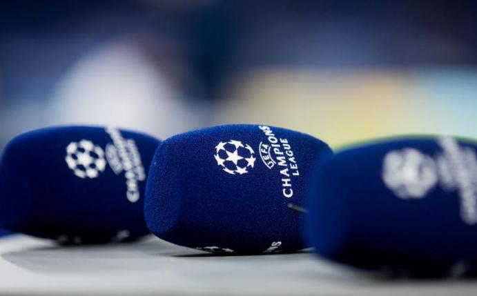 Mikrofone mit dem Logo der Champions League liegen vor einem Spiel auf einem Tisch. Foto: Rolf Vennenbernd/dpa