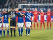 Die Teams von Schalkes und Leipzig nehmen an einer Gedenkminute teil. Foto: Bernd Thissen/dpa