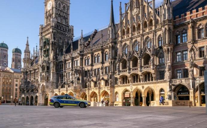 Ein Polizeiauto fährt über den fast leeren Marienplatz. Foto: Peter Kneffel/dpa