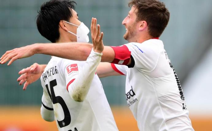 Die Frankfurter Daichi Kamada (l) und David Abraham feiern nach Spielende den Sieg in Wolfsburg. Foto: Swen Pförtner/dpa-Pool/dpa