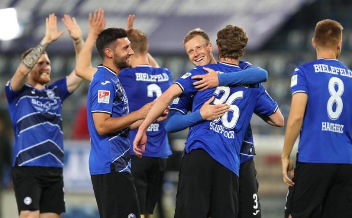 Brian Behrendt (2.vr) von Arminia Bielefeld feiert mit Sven Schipplock und weiteren Mitspielern den Sieg. Foto: Friso Gentsch/dpa-pool/dpa
