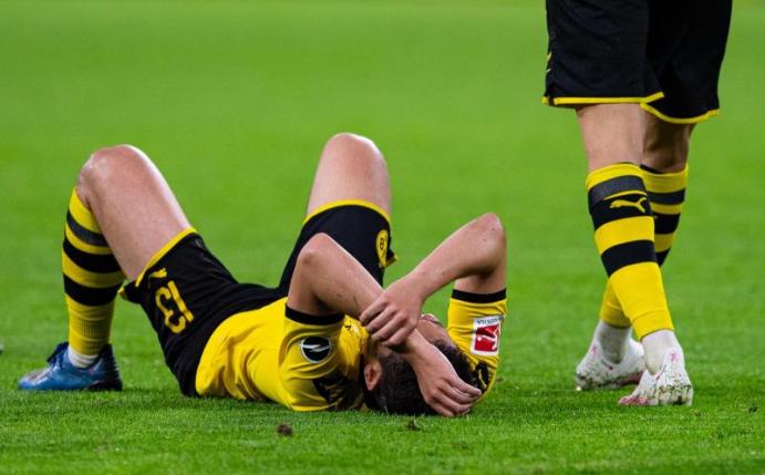 BVB-Spieler Raphael Guerreiro liegt auf dem Rasen. Foto: Guido Kirchner/dpa-pool/dpa