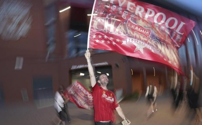 Ein Fan des FC Liverpool schwenkt feiert seinen Verein. Foto: Jon Super/AP/dpa