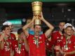 Münchens Thomas Müller hält die Trophäe nach dem Spiel hoch. Foto: Alexander Hassenstein/Getty Images Europe/Pool/dpa