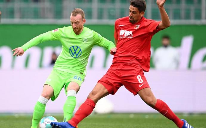 Wolfsburgs Maximilian Arnold (l) kämpft mit Augsburgs Rani Khedira um den Ball. Foto: Swen Pförtner/dpa