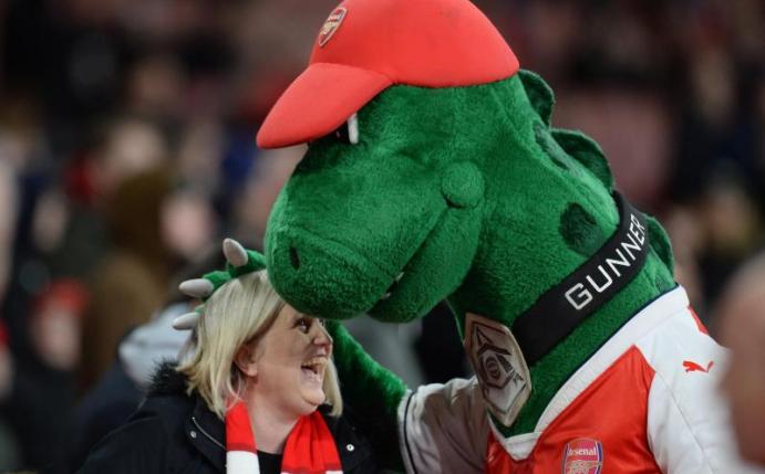 Bei den Fans beliebt Arsenal-Maskottchen «Gunnersaurus» umarmt vor Spielbeginn eine Frau. Foto: picture alliance / Andreas Gebert/dpa