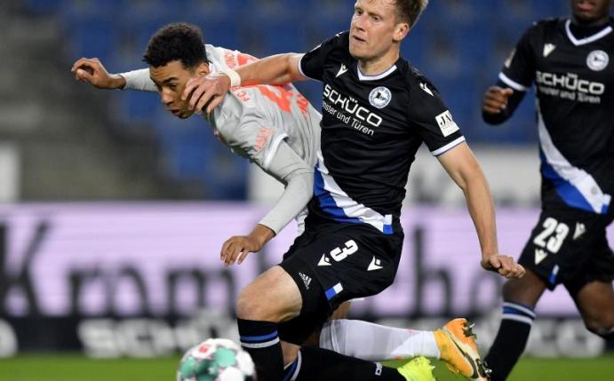 Jamal Musiala (l) von Bayern in Aktion gegen Brian Behrendt (M) von Bielefeld. Foto: Martin Meissner/AP-Pool/dpa