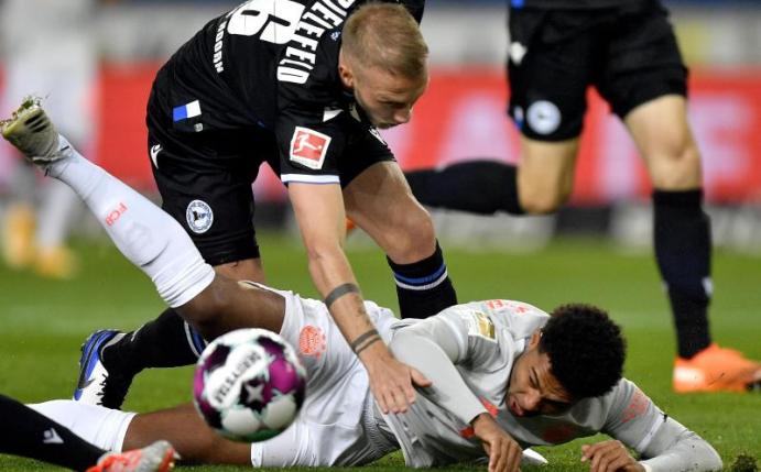 Bayern Münchens Serge Gnabry (unten) im Zweikampf mit dem Bielefelder Mike van der Hoorn. Foto: Martin Meissner/AP-Pool/dpa