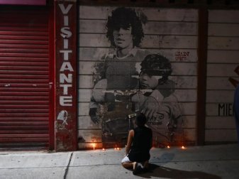 Ein Junge kniet vor einem mit Kerzen dekorierten Wandbild von Diego Maradona in Argentinien. Foto: Marcos Brindicci/AP/dpa Ein Junge kniet vor einem mit Kerzen dekorierten Wandbild von Diego Maradona in Argentinien. Foto: Marcos Brindicci/AP/dpa