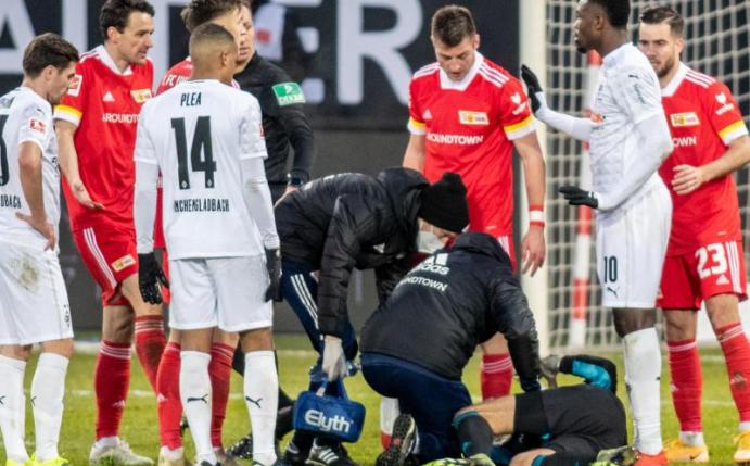 Berlins Torwart Andreas Luthe (3.v.r) liegt nach Zusammenstoß mit dem Gladbacher Marcus Thuram (2.v.r) am Boden. Foto: Andreas Gora/dpa Pool/dpa