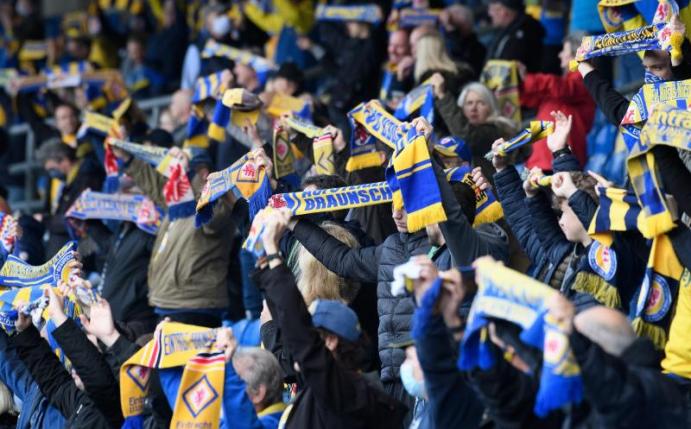 Fans von Eintracht Braunschweig zeigen 2020 im Stadion ihre Schals vor einem Heimspiel. Foto: Swen Pförtner/dpa