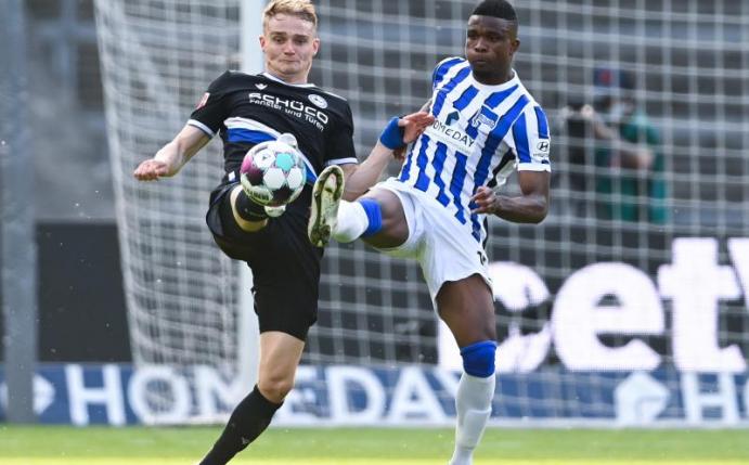 Bielefelds Amos Pieper und Herthas Jhon Cordoba (r) gehen mit gestreckten Beinen zum Ball. Foto: Soeren Stache/dpa-Pool/dpa