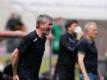 Kölns Trainer Friedhelm Funkel versucht seine Spieler auf dem Platz zu erreichen - im Hintergrund steht Freiburgs Trainer Christian Streich. Foto: Rolf Vennenbernd/dpa