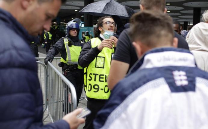 Stewards kontrollieren die elektronischen Tickets der Fans beim Betreten des Wembley-Stadions. Foto: David Cliff/AP/dpa