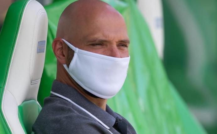 Wolfsburgs Trainer Stephan Lerch sitzt vor dem Spiel mit Mund-Nasen-Schutz auf der Auswechselbank. Foto: Swen Pförtner/dpa