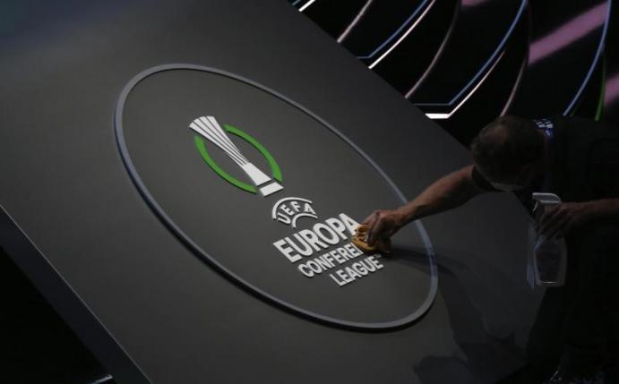 Ein Mitarbeiter reinigt das Logo der UEFA Europa Conference League. Foto: Emrah Gurel/AP/dpa