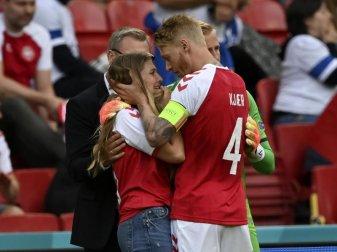 Dänemarks Mannschaftskapitän Simon Kjaer (r) spricht mit einer Frau, die das Trikot des dänischen Spielers Eriksen trägt, der auf einer Trage vom Feld gebracht wurde. Foto: Stuart Franklin/Getty Pool/AP/dpa Dänemarks Mannschaftskapitän Simon Kjaer (r) spricht mit einer Frau, die das Trikot des dänischen Spielers Eriksen trägt, der auf einer Trage vom Feld gebracht wurde. Foto: Stuart Franklin/Getty Pool/AP/dpa