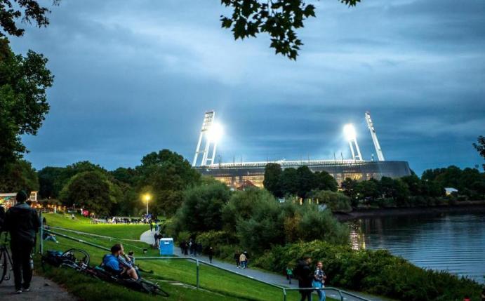Fans auf dem Weg zum beleuchteten Weserstadion. Foto: Sina Schuldt/dpa