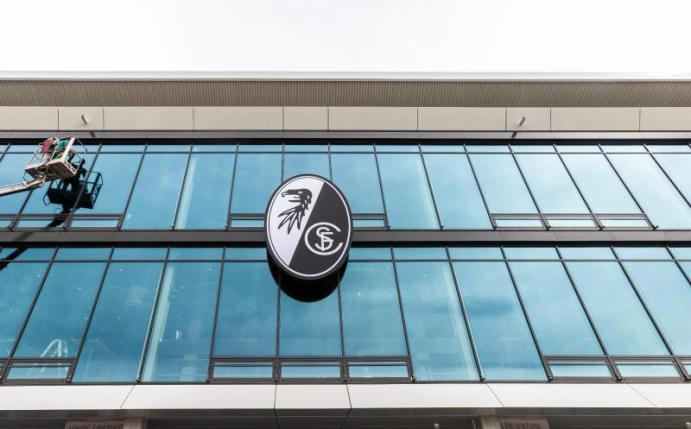 Das Logo des SC Freiburg hängt über dem Eingang des neuen Stadions. Der Verein konnte trotz Corona eine erfolgreiche Bilanz vorlegen. Foto: Philipp von Ditfurth/dpa