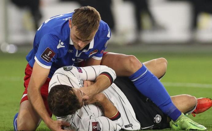 Jens Hofer aus Liechtenstein (l) beugt sich über den gefoulten Leon Goretzka. Foto: Christian Charisius/dpa