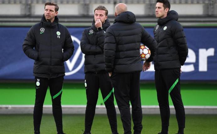 Vor dem Abflug nach Sevilla war Corona wieder ein Thema: Wolfsburgs Trainer Florian Kohfeldt (l) steht mit seinem Team zusammen. Foto: Swen Pförtner/dpa