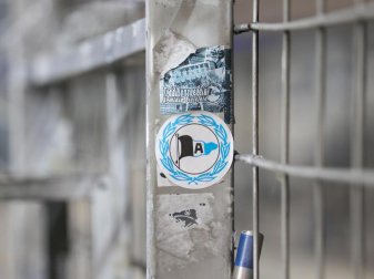 Ein Aufkleber mit dem Logo von Arminia Bielefeld klebt auf einem Zaun. Foto: Friso Gentsch/dpa Ein Aufkleber mit dem Logo von Arminia Bielefeld klebt auf einem Zaun. Foto: Friso Gentsch/dpa