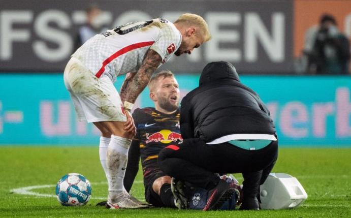 Konrad Laimer von RB Leipzig (M) sitzt verletzt auf dem Spielfeld und wird behandelt. Foto: Matthias Balk/dpa