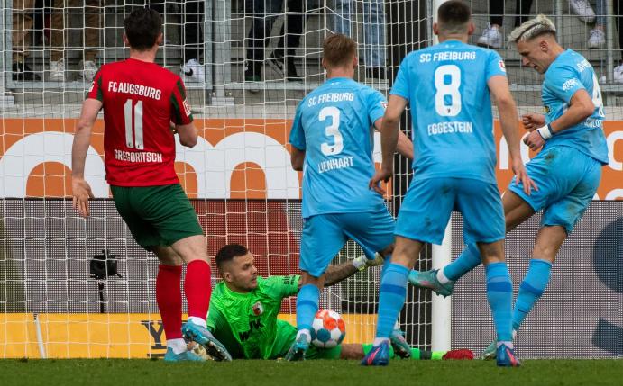 Augsburgs Michael Gregoritsch (l) und Torwart Rafal Gikiewicz können das 1:2 durch Freiburgs Nico Schlotterbeck (r) nicht verhindern.