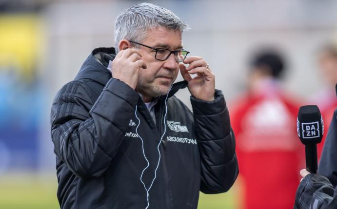 Union-Trainer Urs Fischer richtet seine Kopfhörer im Interview vor Spielbeginn.