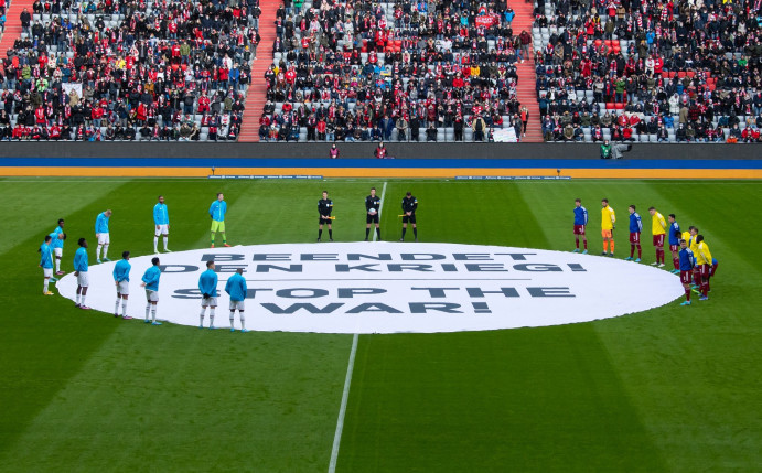 Die Spieler von München und von Leverkusen stehen um ein Banner mit «Beendet den Krieg! - Stop the War!».