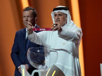 Der ehemalige katarische Fußballnationalspieler Adel Ahmed MalAllah hält das Los mit dem Teilnehmer Japan in der Hand. Der ehemalige katarische Fußballnationalspieler Adel Ahmed MalAllah hält das Los mit dem Teilnehmer Japan in der Hand.