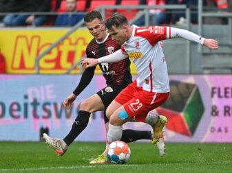 Regensburgs Steve Breitkreuz (r) versucht den Ball im Zweikampf vor Ingolstadts Florian Pick abzuschirmen.