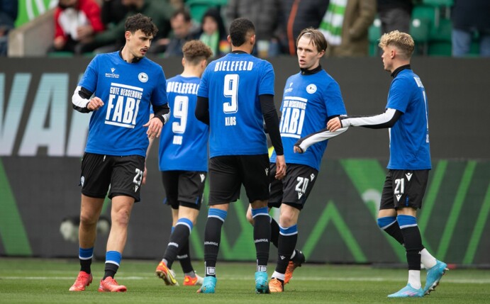 Spieler von Bielefeld tragen beim Aufwärmen ein Trikot mit der Rückennummer 9 und der Aufschrift "Gute Besserung Fabi".