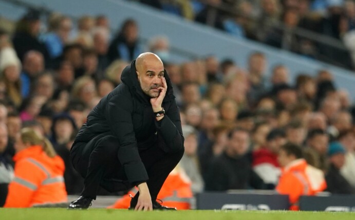 Pep Guardiola, Trainer von Manchester City, hockt an der Seitenlinie und studiert das Spiel seiner Mannschaft.