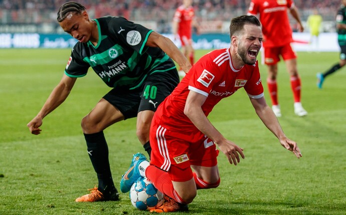 Berlins Niko Gießelmann (r) geht nach einem Foul von Jamie Leweling von Greuther Fürth zu Boden.