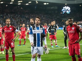 Bielefelds Torhüter Stefan Ortega Moreno (M) und seine Teamkollegen stehen vor der Fankurve. Links Bielefelds Manuel Prietl, rechts Bielefelds Nathan de Medina.