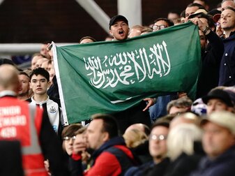 Ein Fan von Newcastle United hält die Fahne von Saudi-Arabien während eines Spiels hoch. Ein Fan von Newcastle United hält die Fahne von Saudi-Arabien während eines Spiels hoch.