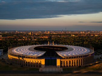 Die untergehende Sonne scheint auf das Olympiastadion in Berlin.